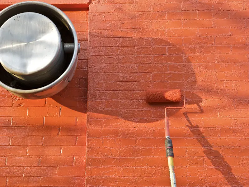 Rodillo pintando una pared de ladrillo